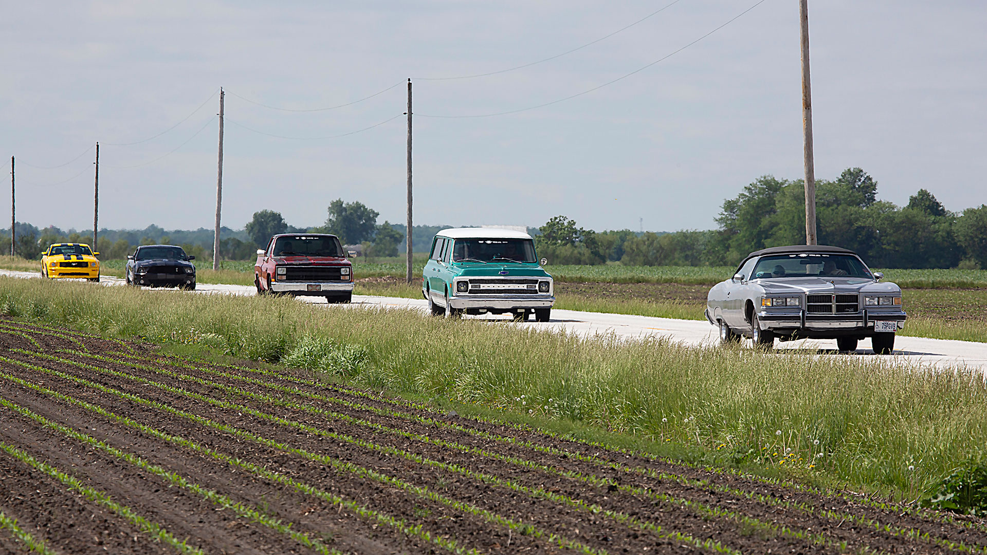 Classic cars driving through farm land